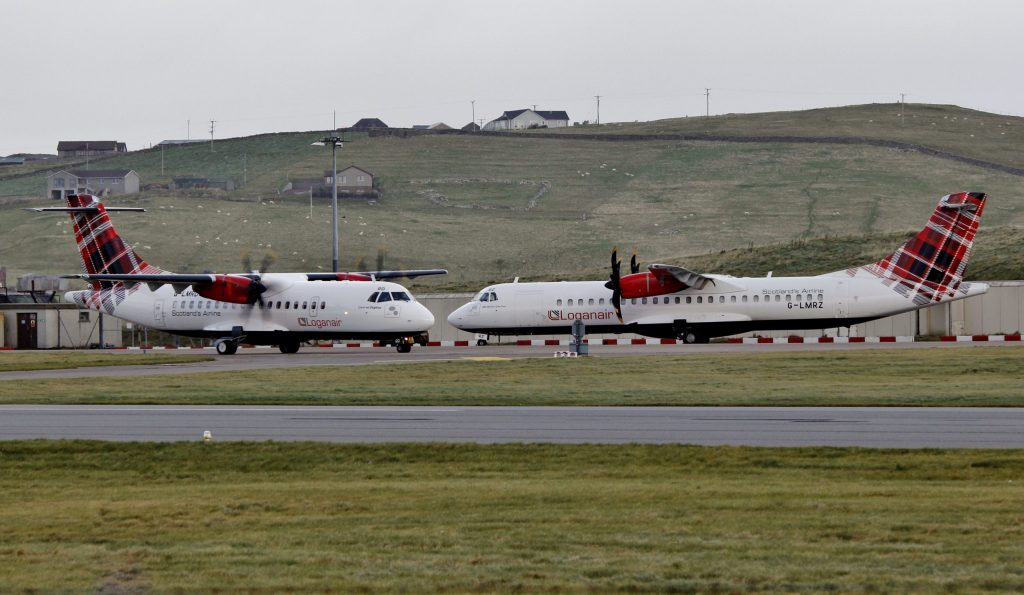 Two Loganair aircraft pass each other on the taxiway.