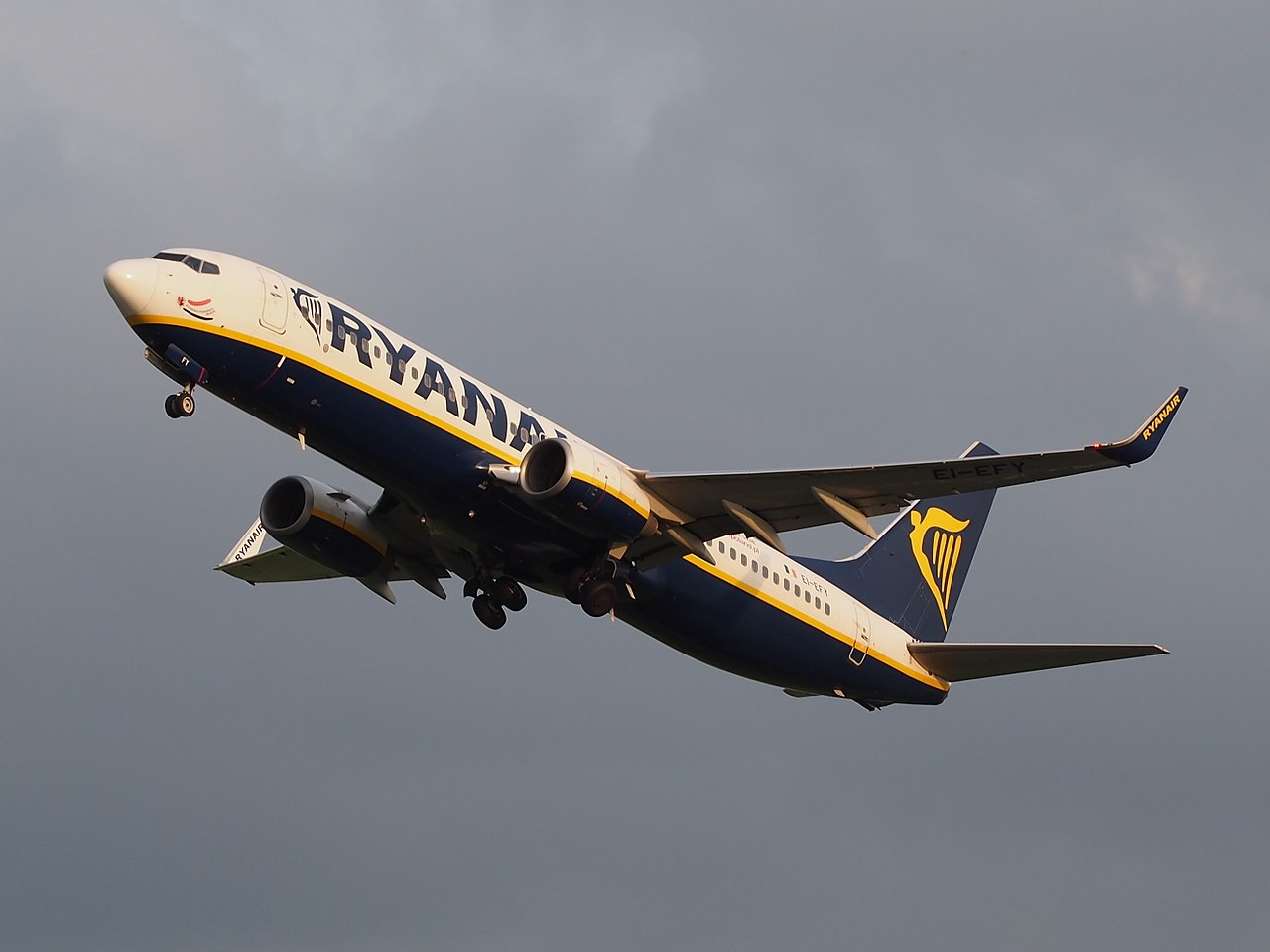 A Ryanair Boeing 737 climbs in an overcast sky.