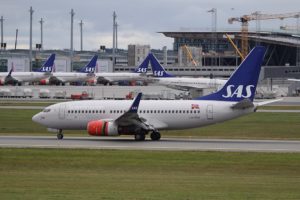 An SAS Scandinavia airlines Boeing 737 taxiing with more SAS aircraft parked in the background.