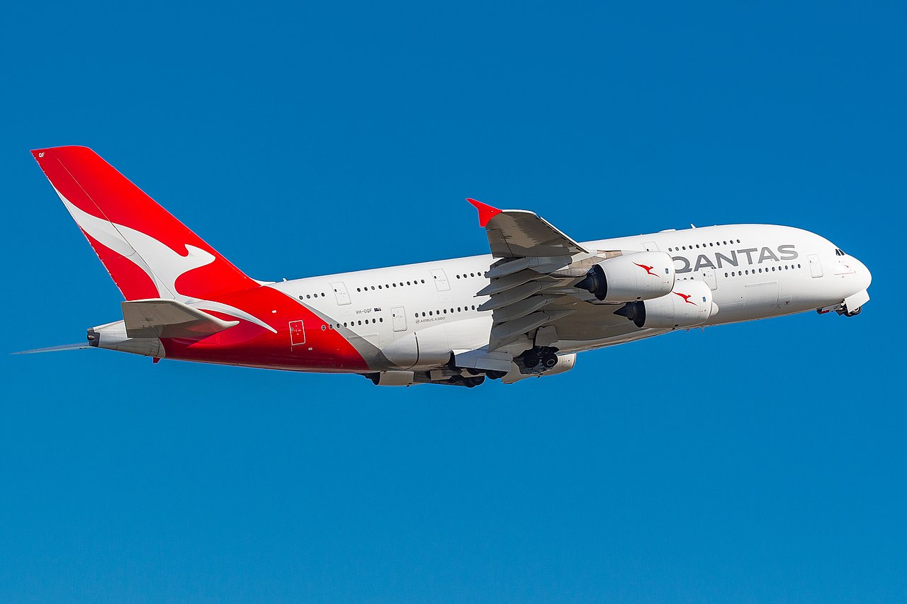 A Qantas Airbus A380 flying against a bright blue sky.