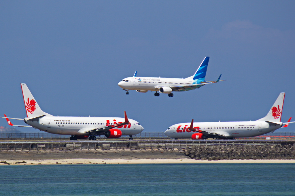 Lion Air aircraft waiting to depart Denpasar as Garuda Indonesia aircraft lands.