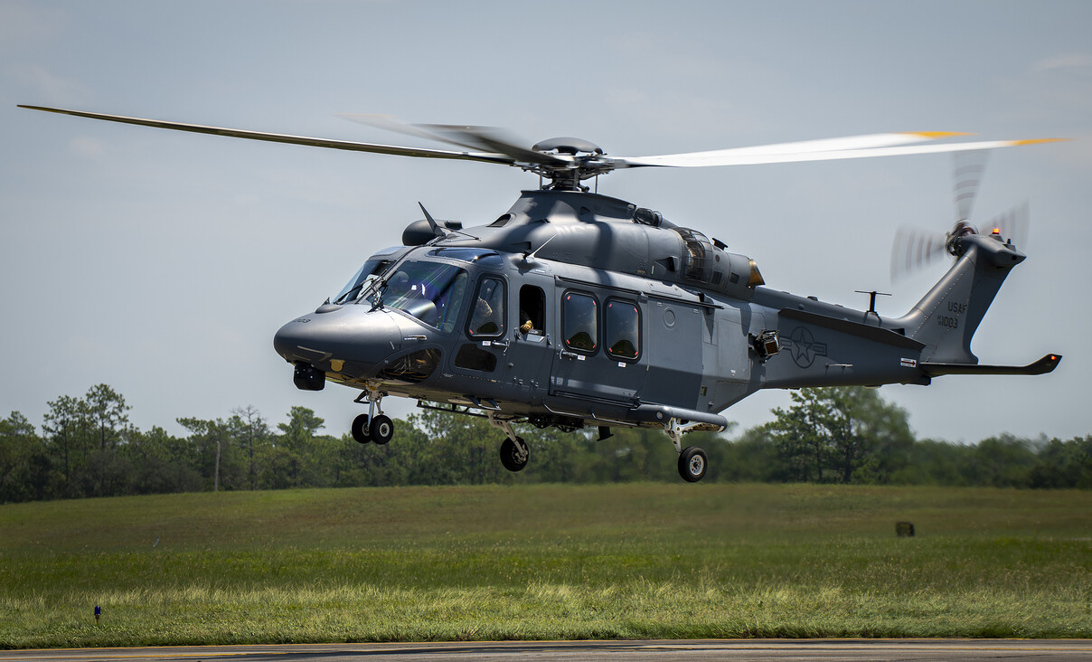 A USAF MH-139A Grey Wolf helicopter hovering in a field.