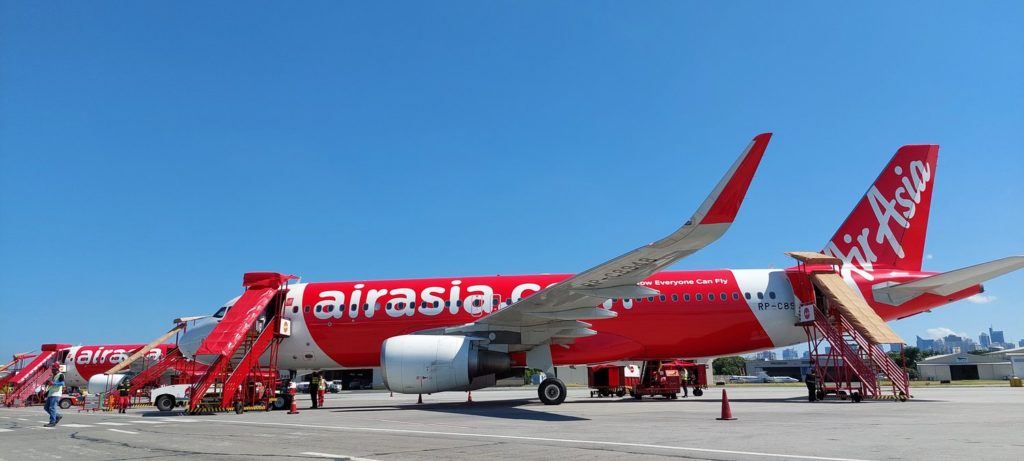 Two AirAsia Philippines aircraft parked under a sunny blue sky.