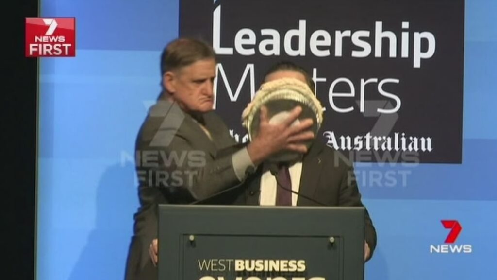 An angry protester squashes a pie in the face of Qantas CEO Alan Joyce