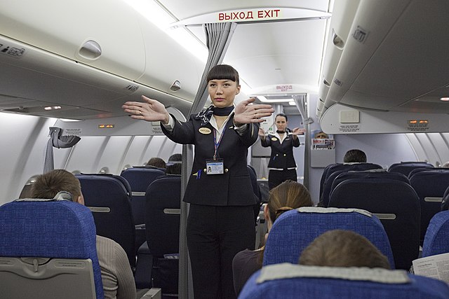Flight attendants perform pre-takeoff air safety passenger briefing.