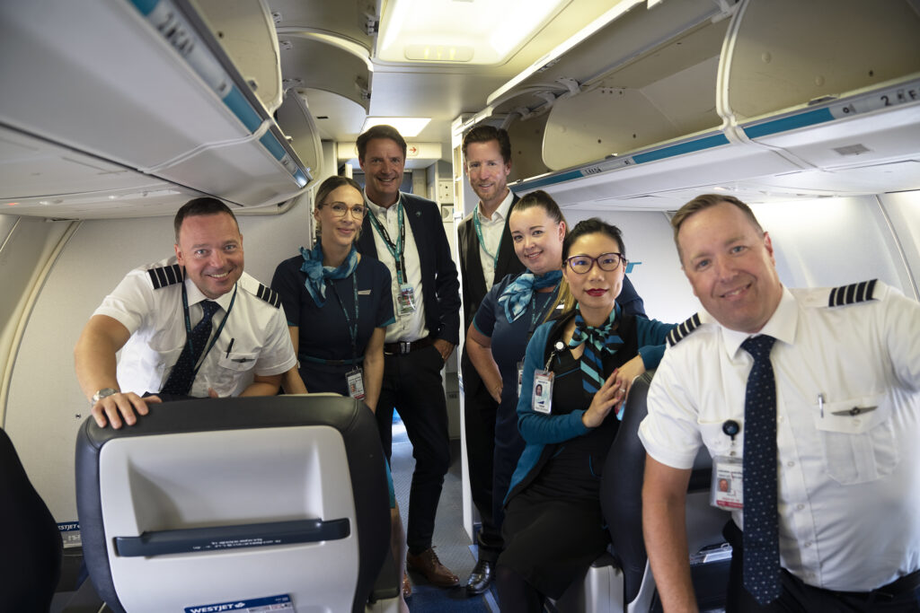 Westjet flight crew and cabin crew members pose in the passenger cabin.