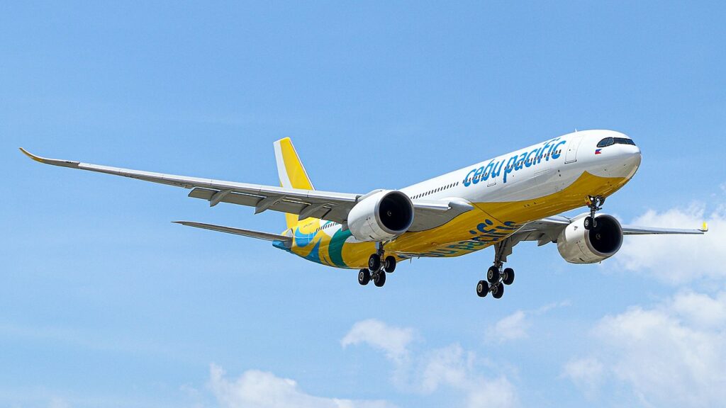 A Cebu Pacific Airbus approaching to land in a blue sky.