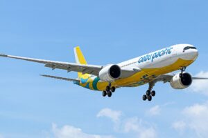 A Cebu Pacific Airbus approaching to land in a blue sky.