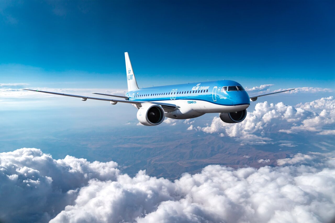 The KLM Cityhopper Embraer E2 jet in flight above clouds.