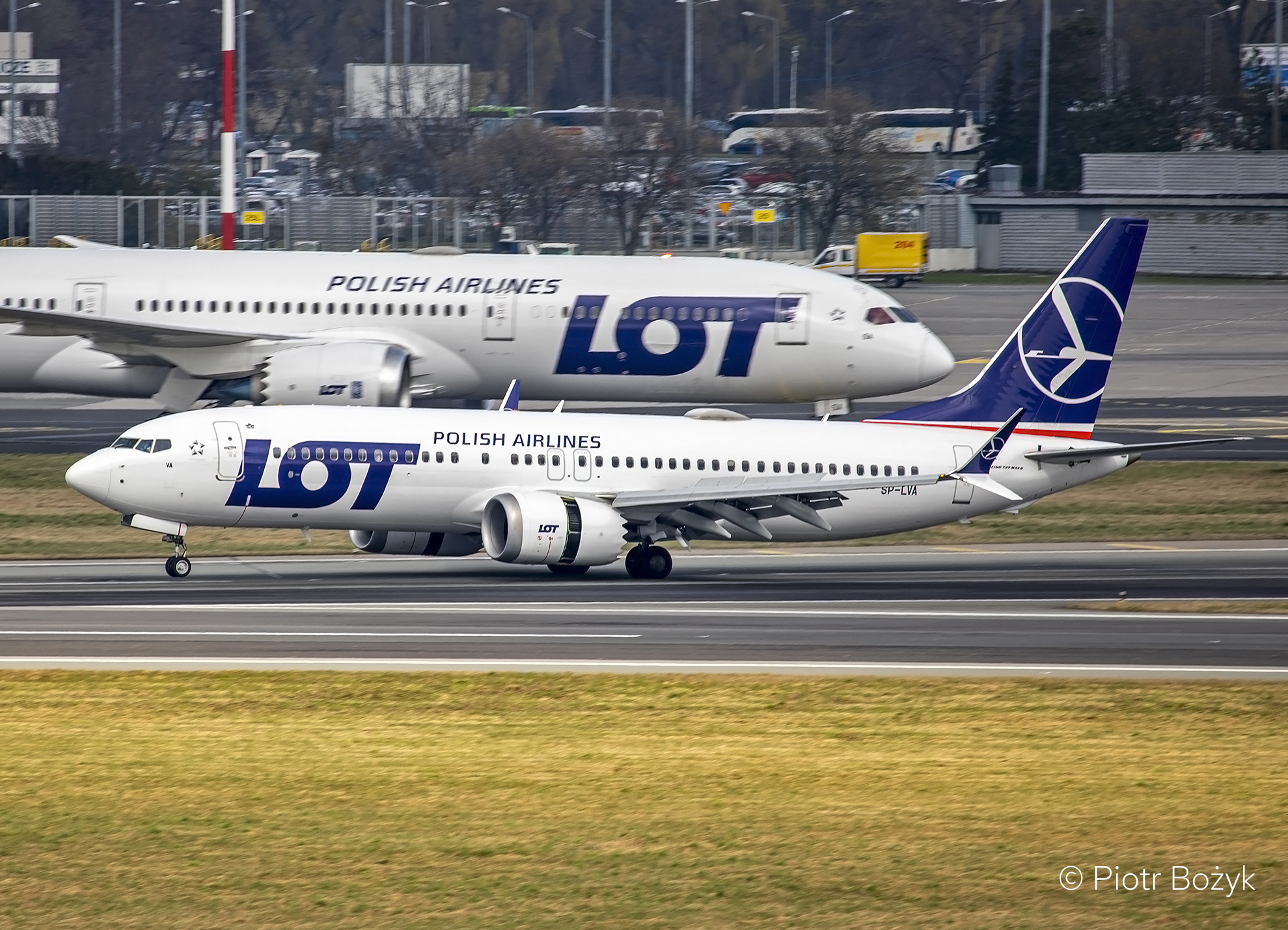 Two LOT Polish Airlines aircraft pass each other on the taxiway.