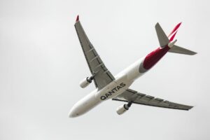 A Qantas jet passes overhead.