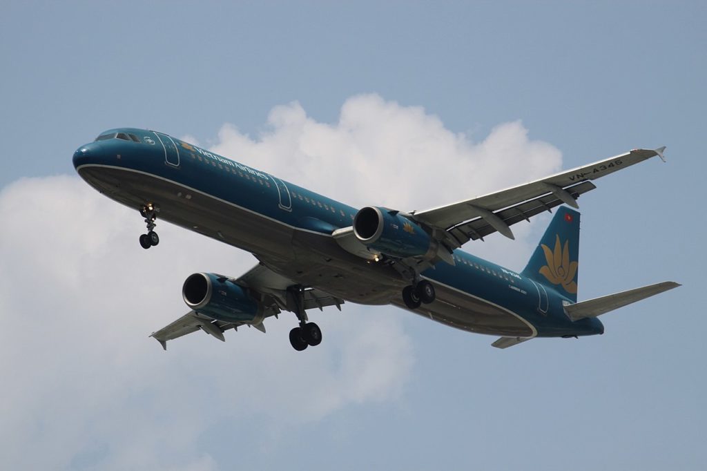 A Vietnam Airlines Airbus A321 flying against a cloudy backdrop.