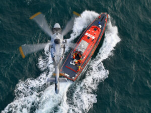 And Airbus H160 helicopter hovers over a search and rescue boat.