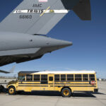 A USAF C-17 Globemaster loading a yellow school bus.