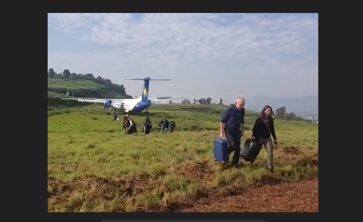 A Rwandair Dash 8 aircraft parked in tall grass after it overran runway on landing.