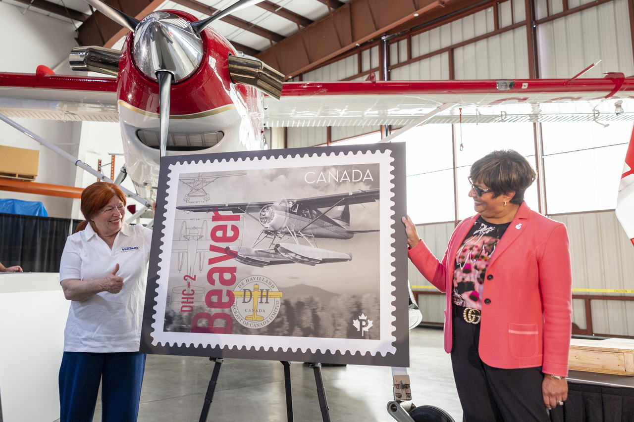 Officials pose with a display of the stamp honouring the de Havilland DHC-2 Beaver aircraft