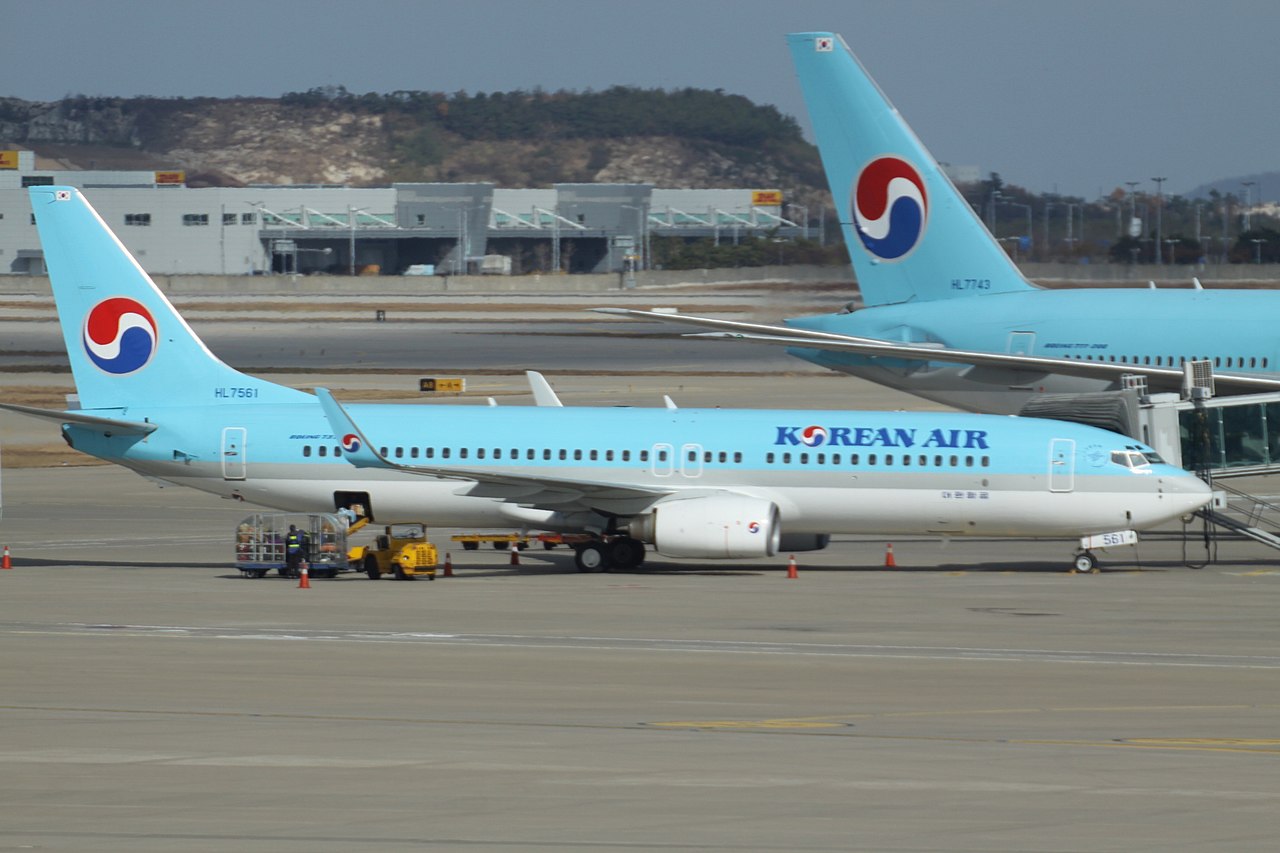 A Korean Air 737 parked in front of a larger Boeing 777 aircraft.