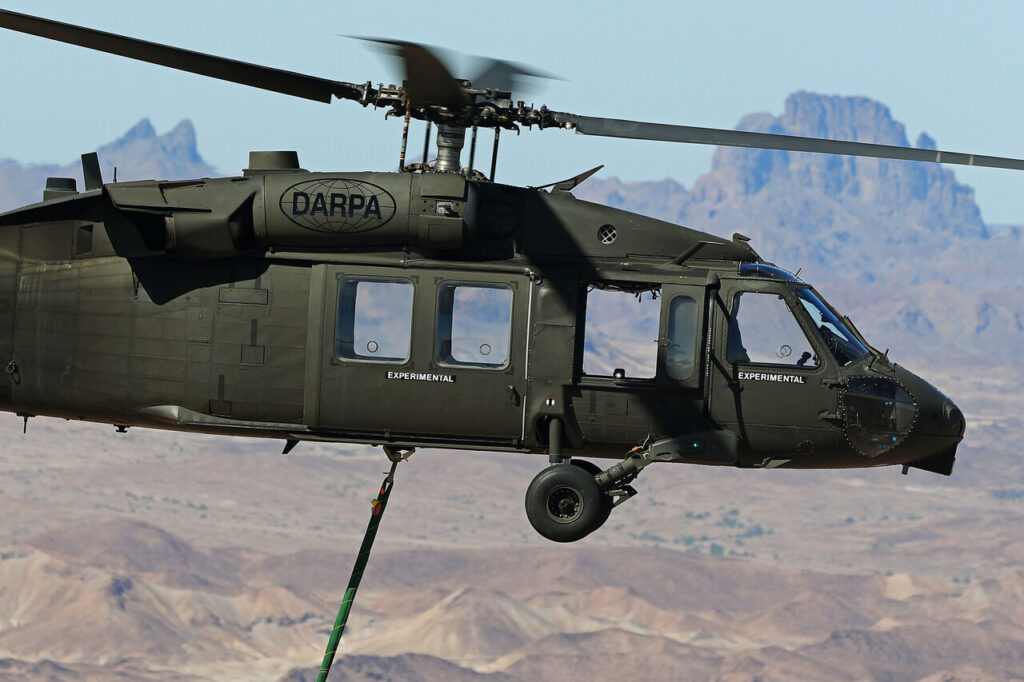 A pilotless Sikorsky DARPA Black Hawk helicopter hovers in the desert.