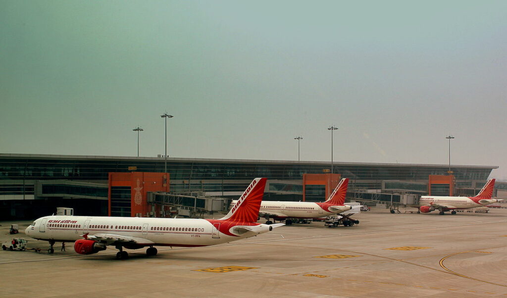 A line of three Air India Airbuses parked at Delhi Airport terminal.