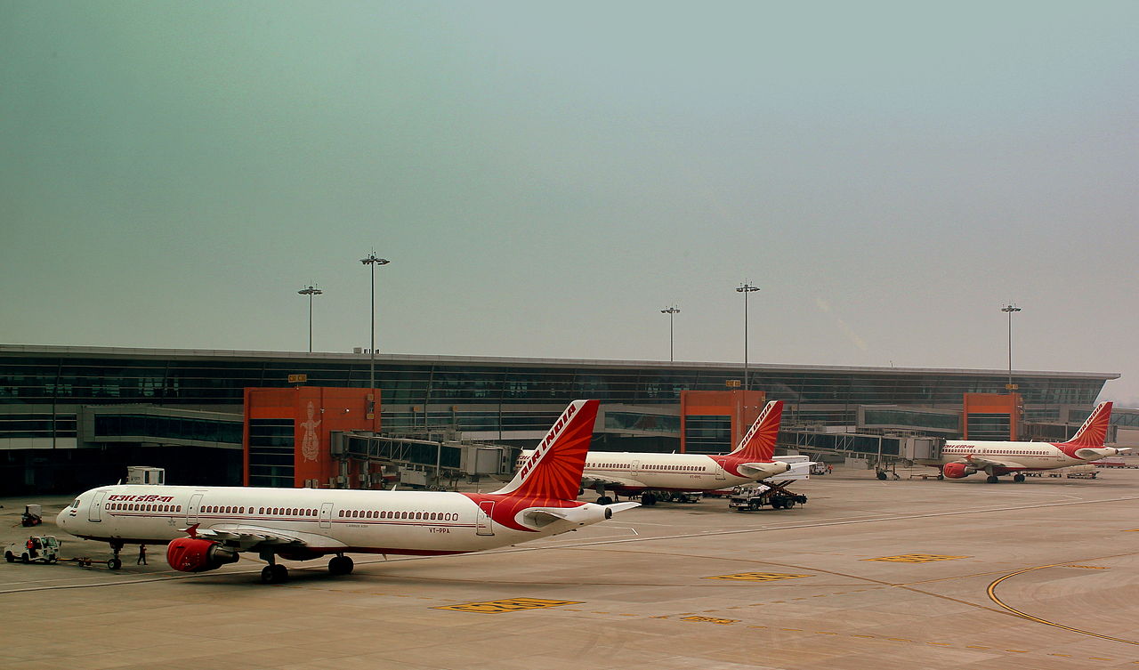 A line of three Air India Airbuses parked at Delhi Airport terminal.
