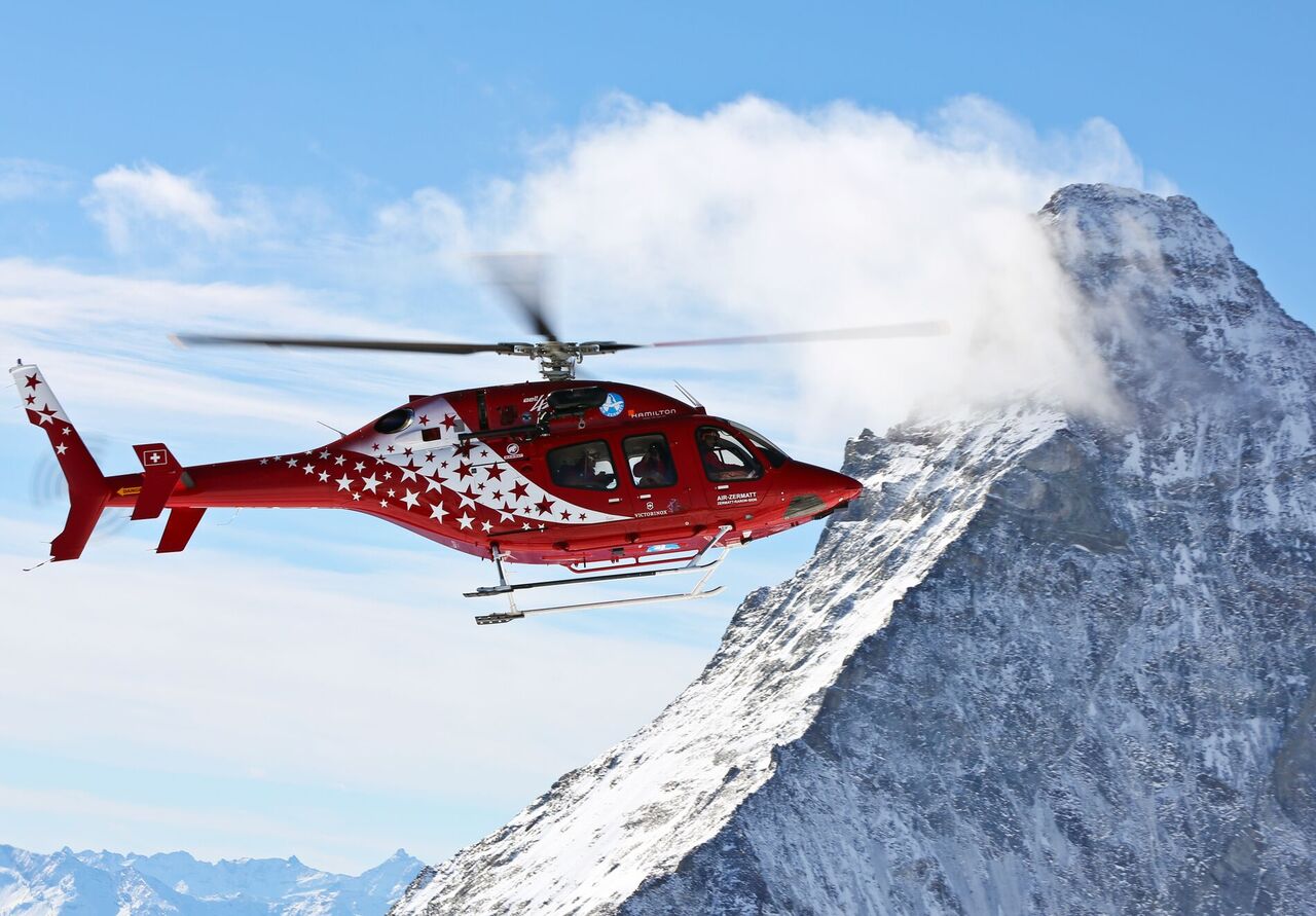 An Air Zermatt Bell 429 helicopter flying in the Swiss Alps