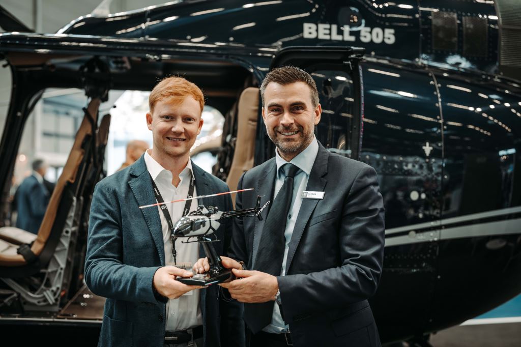 Delegates of Bell Textron and Airbourne stand in front of a Bell 505 helicopter.