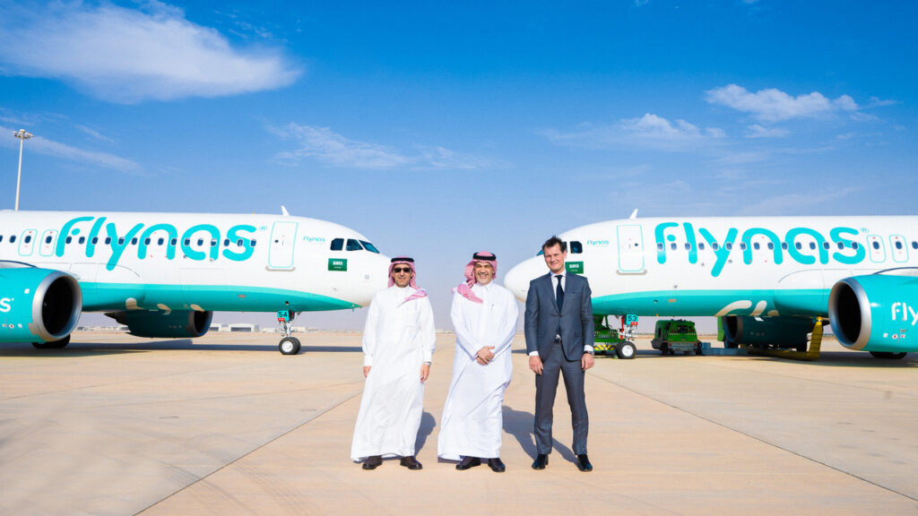 flynas officials stand in front of two new Airbus A320neos parked nose to nose.