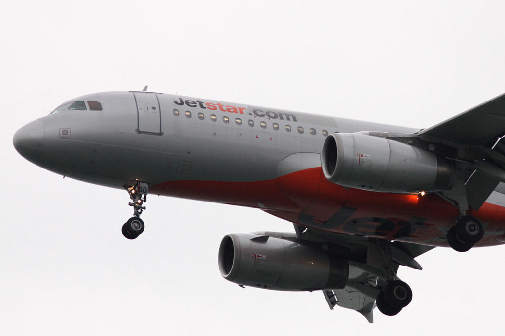 A Jetstar Asia Airbus A320 approaches with landing gear down.