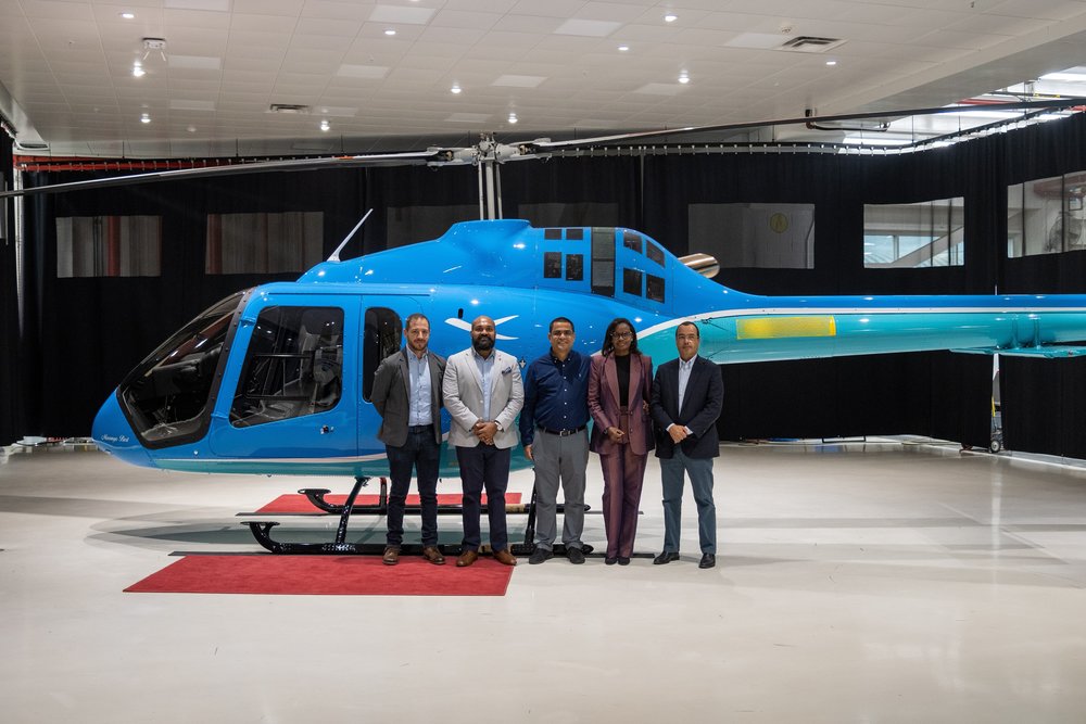 Angolan BESTFLY representatives stand with a Bell 505 helicopter in the hangar.