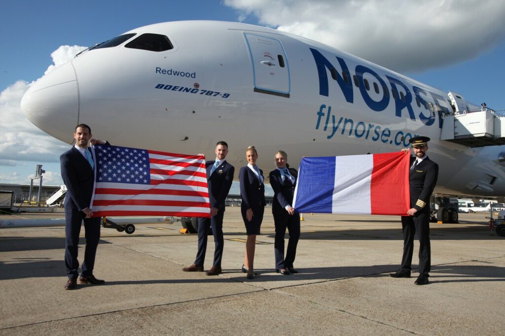 Norse Atlantic Airways flight crew hold up US and French flags in front of a Boeing 787 Dreamliner.