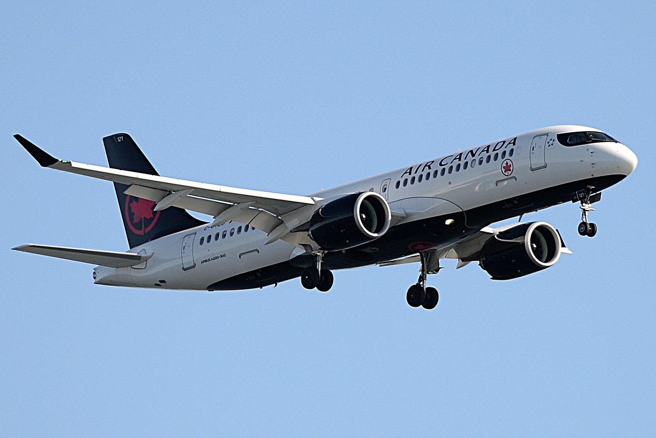 An Air Canada A220 approaches Boston Logan airport with landing gear down.
