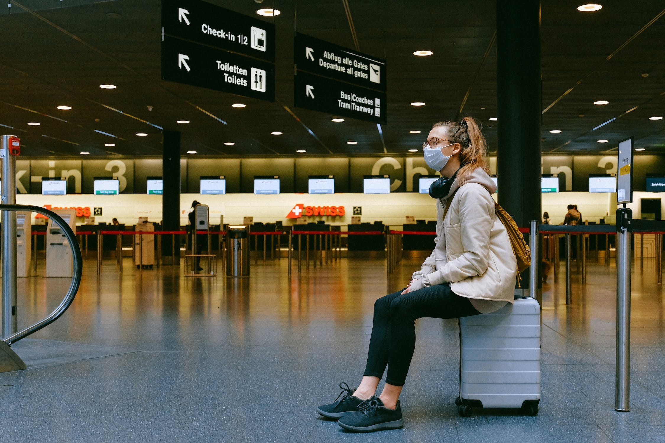 An air travel passenger sits alone in an airport terminal waiting for a flight.