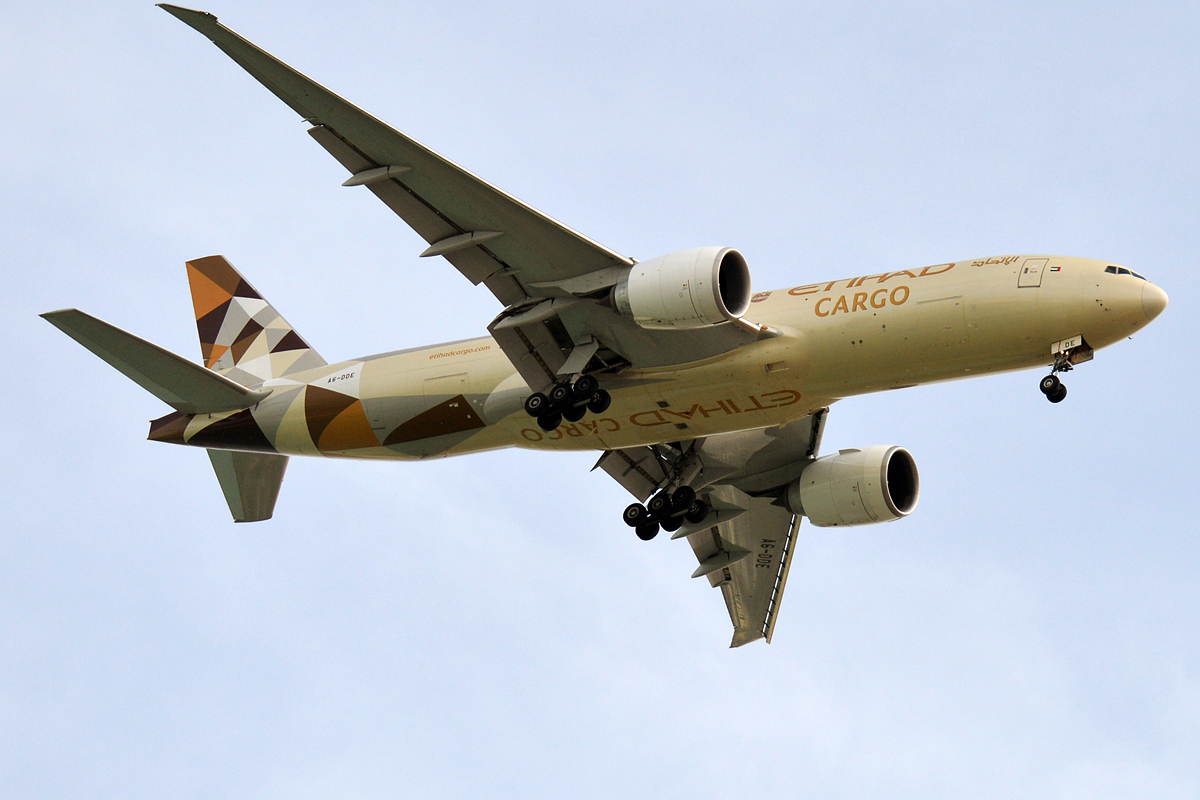 An Etihad Cargo Boeing 777 freighter flies overhead.