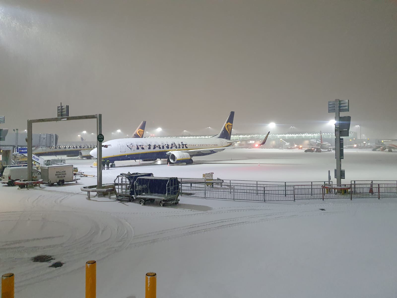 A Ryanair aircraft covered in snow at Stansted Airport.