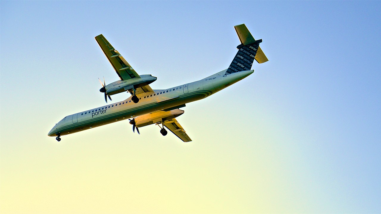 A Porter Airlines Dash-8 aircraft passes overhead.