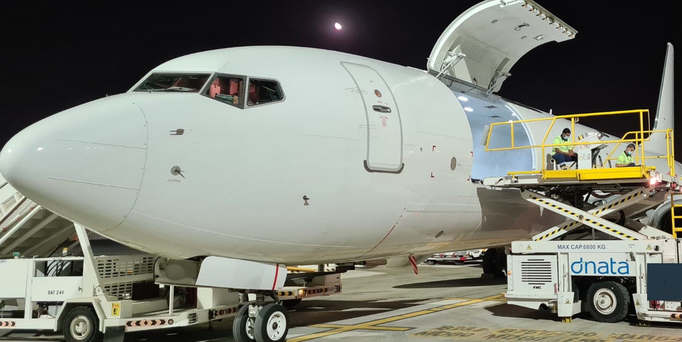A Georgian Airlines Boeing 737 cargo freighter is loaded at night.