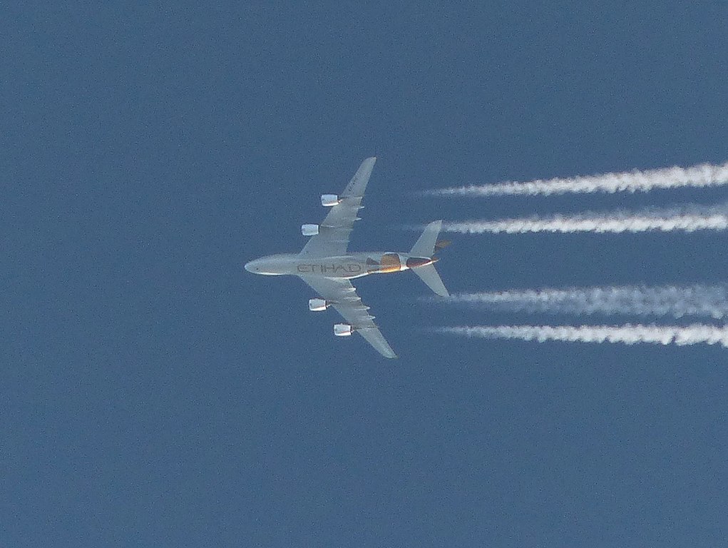 An Etihad Airbus creates contrails overhead.