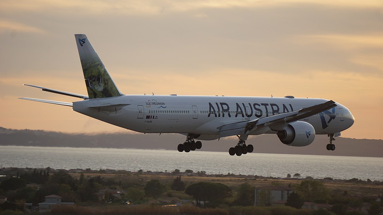 An Air Austral Boeing 777 approaches to land at dusk.
