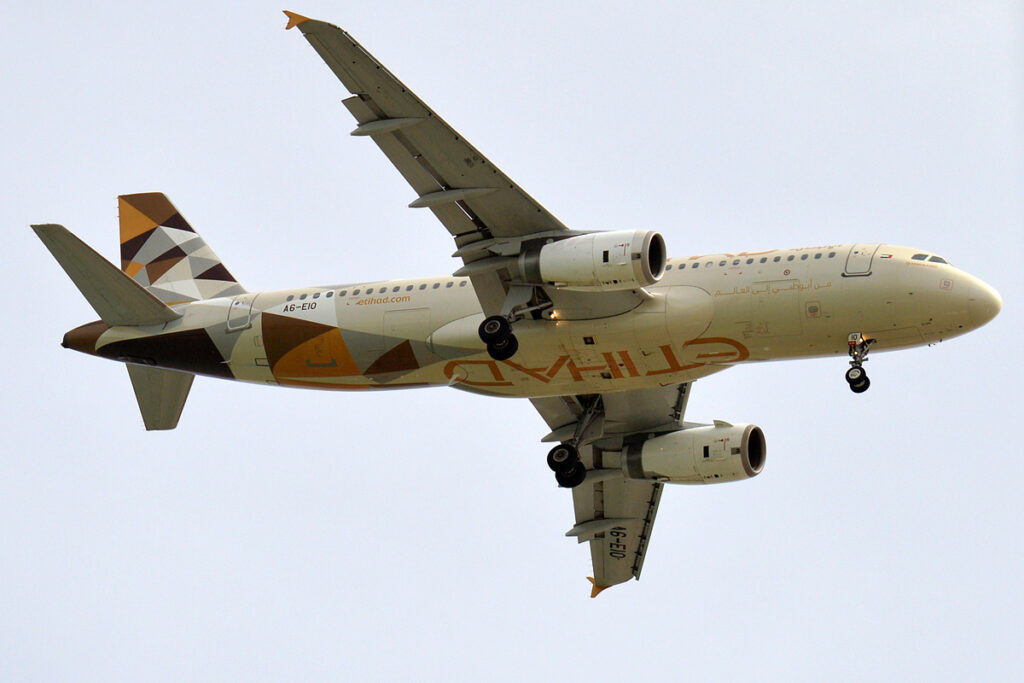 An Etihad Airways A320 passes overhead.