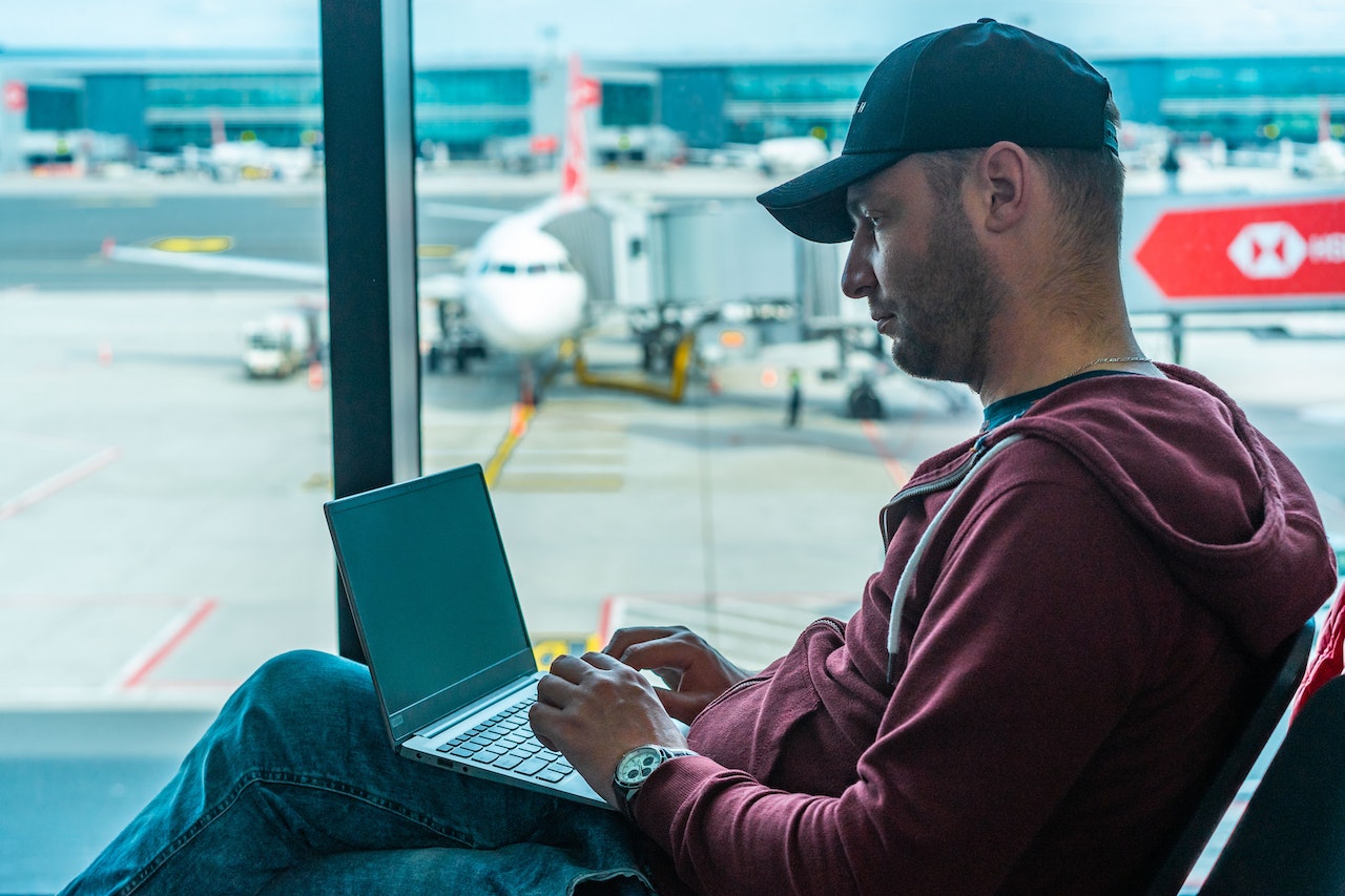 A man works on a laptop in an airport terminal