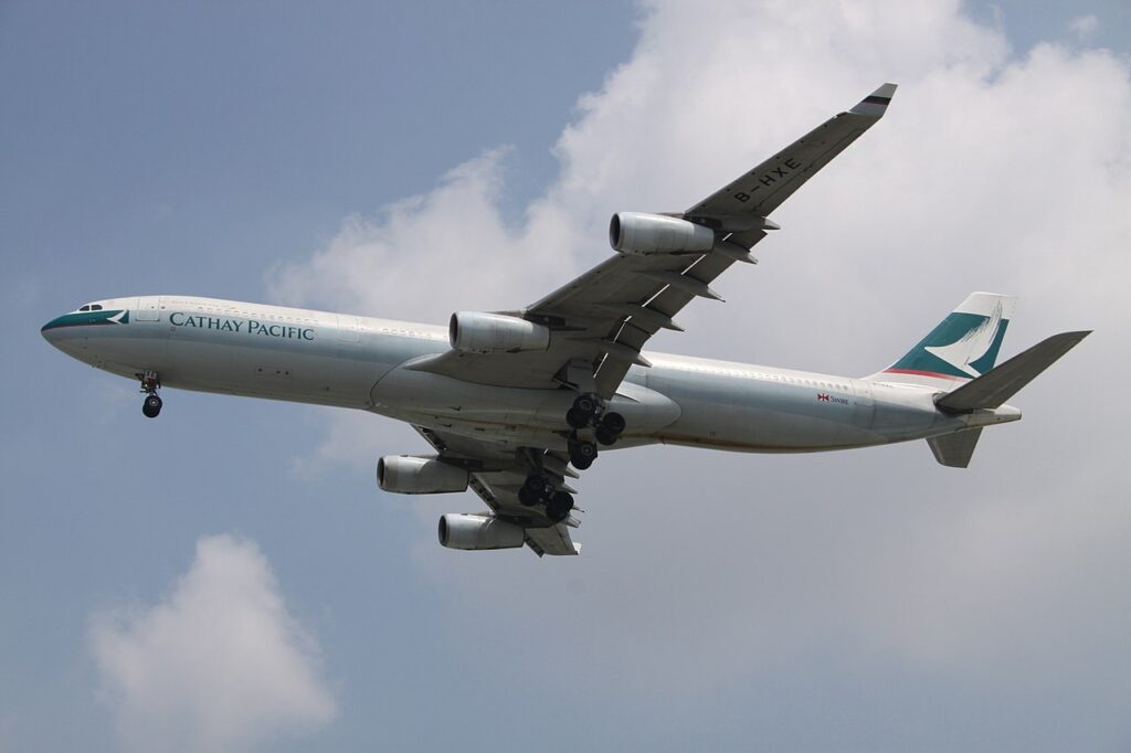 A Cathay Pacific Airbus A340 passes overhead.