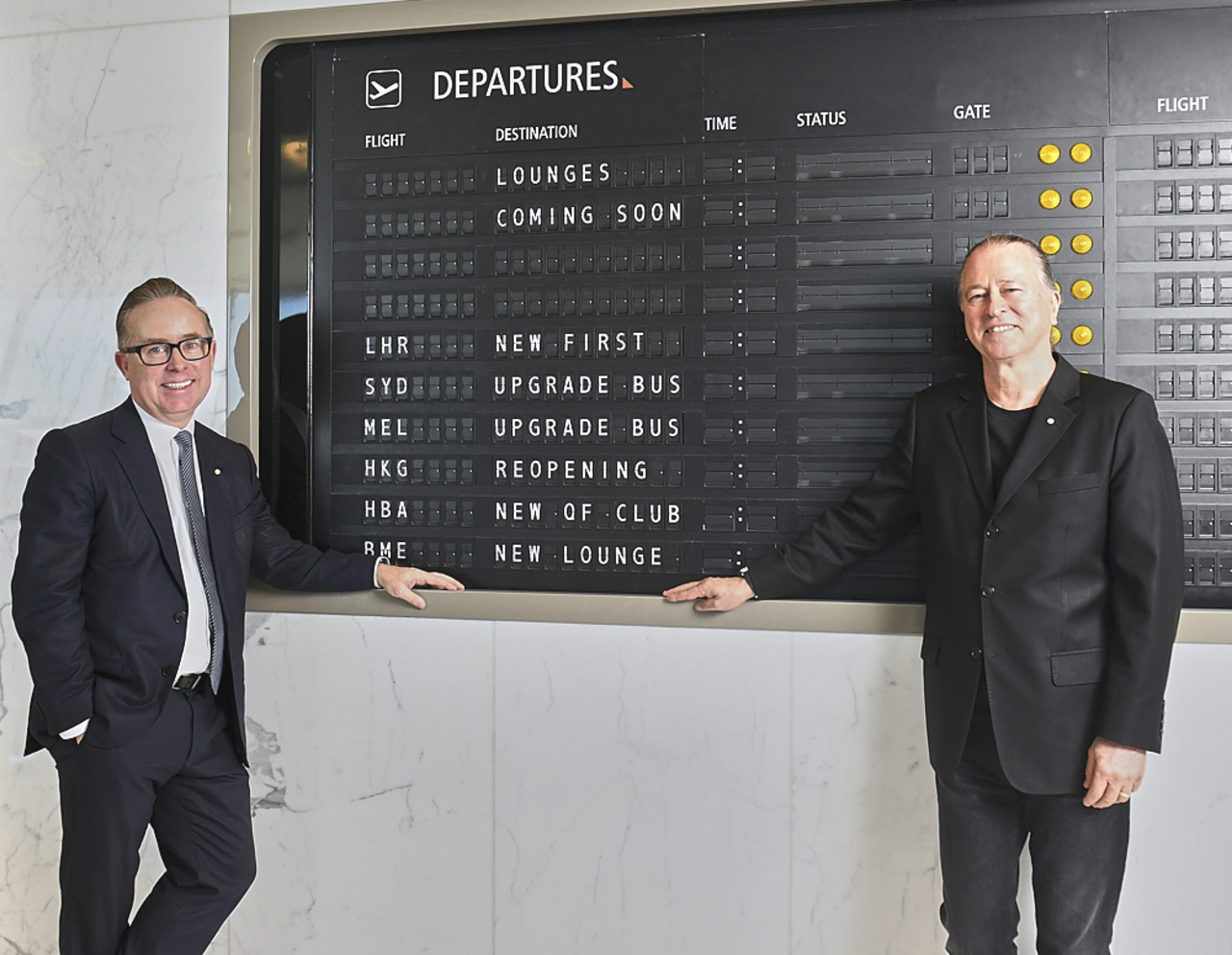 Qantas execs with a departure board showing new lounge openings.