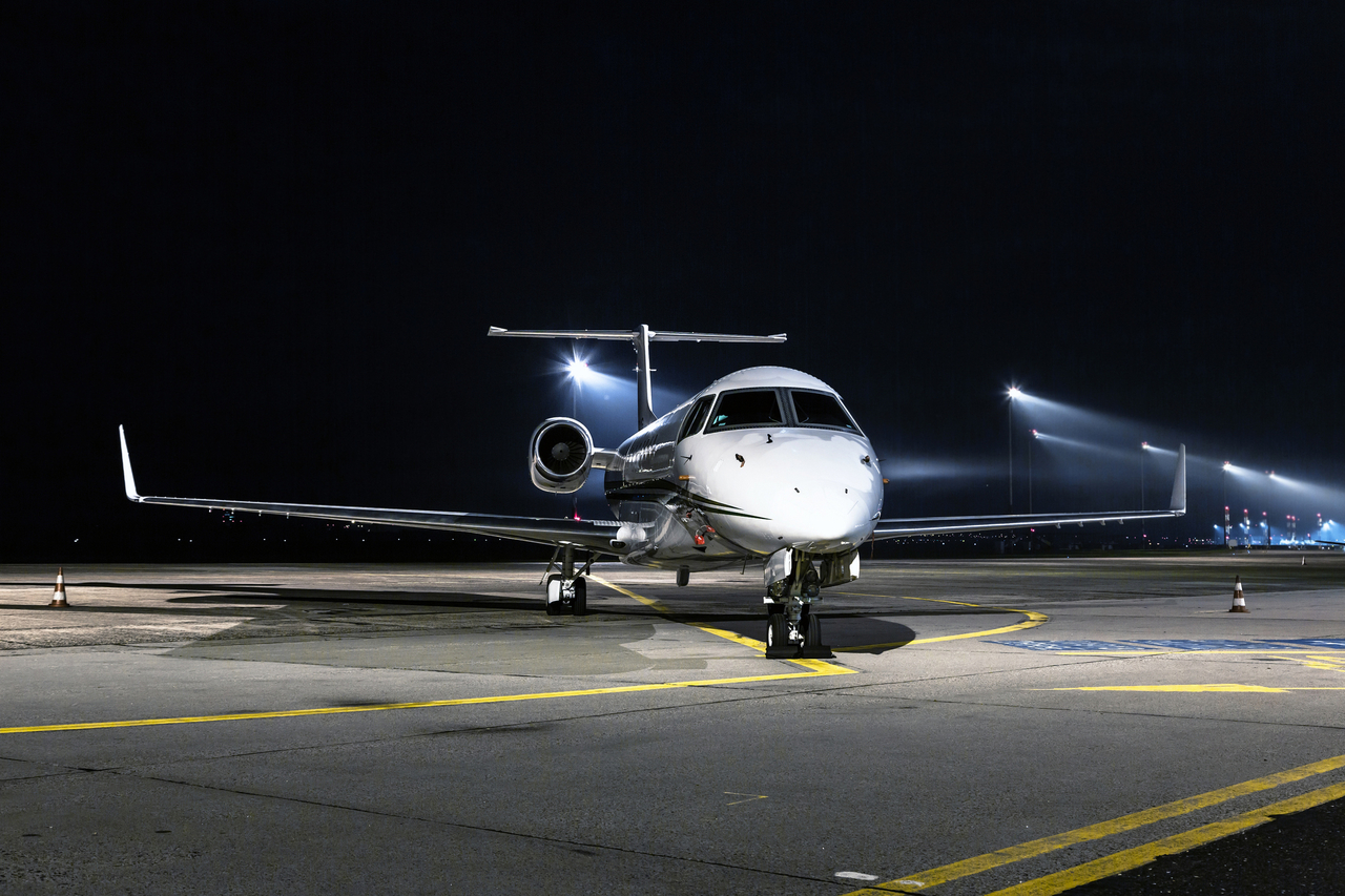 An Equinox Charter jet parked on the ramp at night.