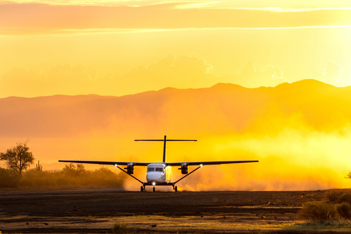 A Cessna SkyCourier on a dirt runway at dawn.