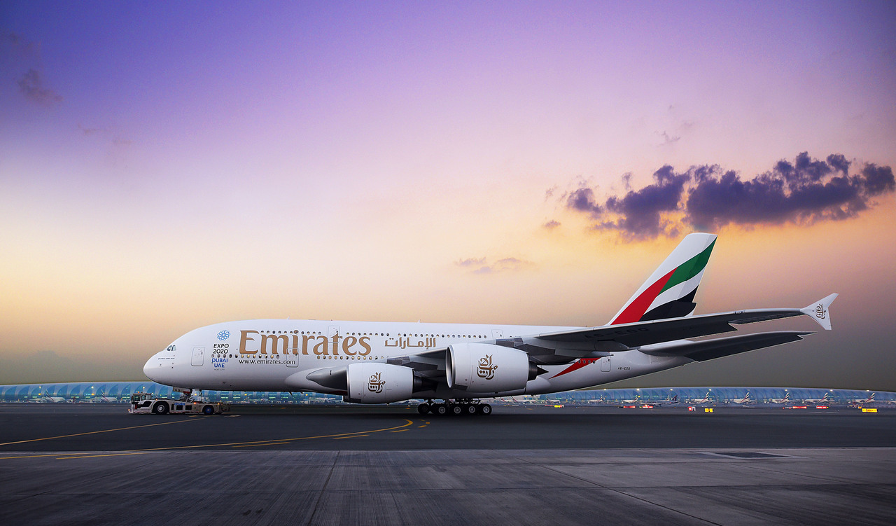 An Emirates A380 on the runway at dusk.