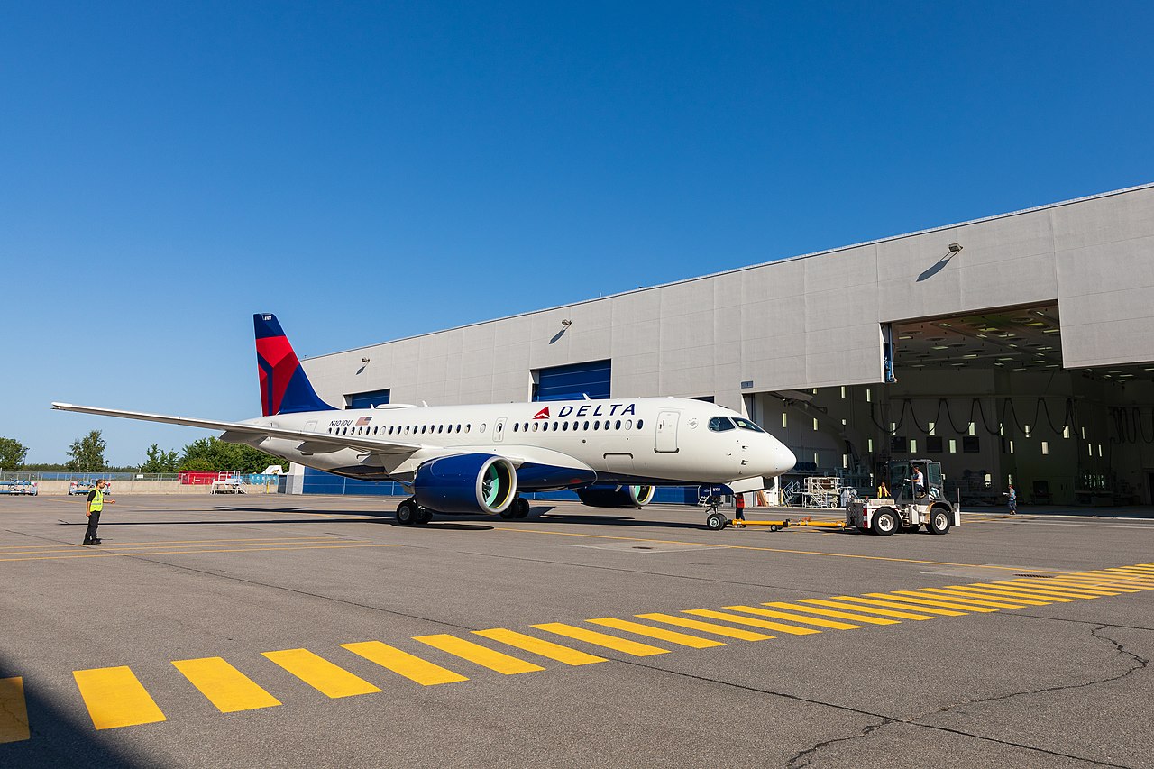 A Delta Air lines Airbus A220 parked in front of the hangar