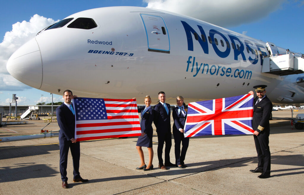 Staff stand in front of Norse Atlantic aircraft with US and UK flags.