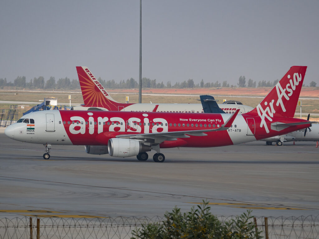A Tata Group Air India and an Air Asia India aircraft parked together.