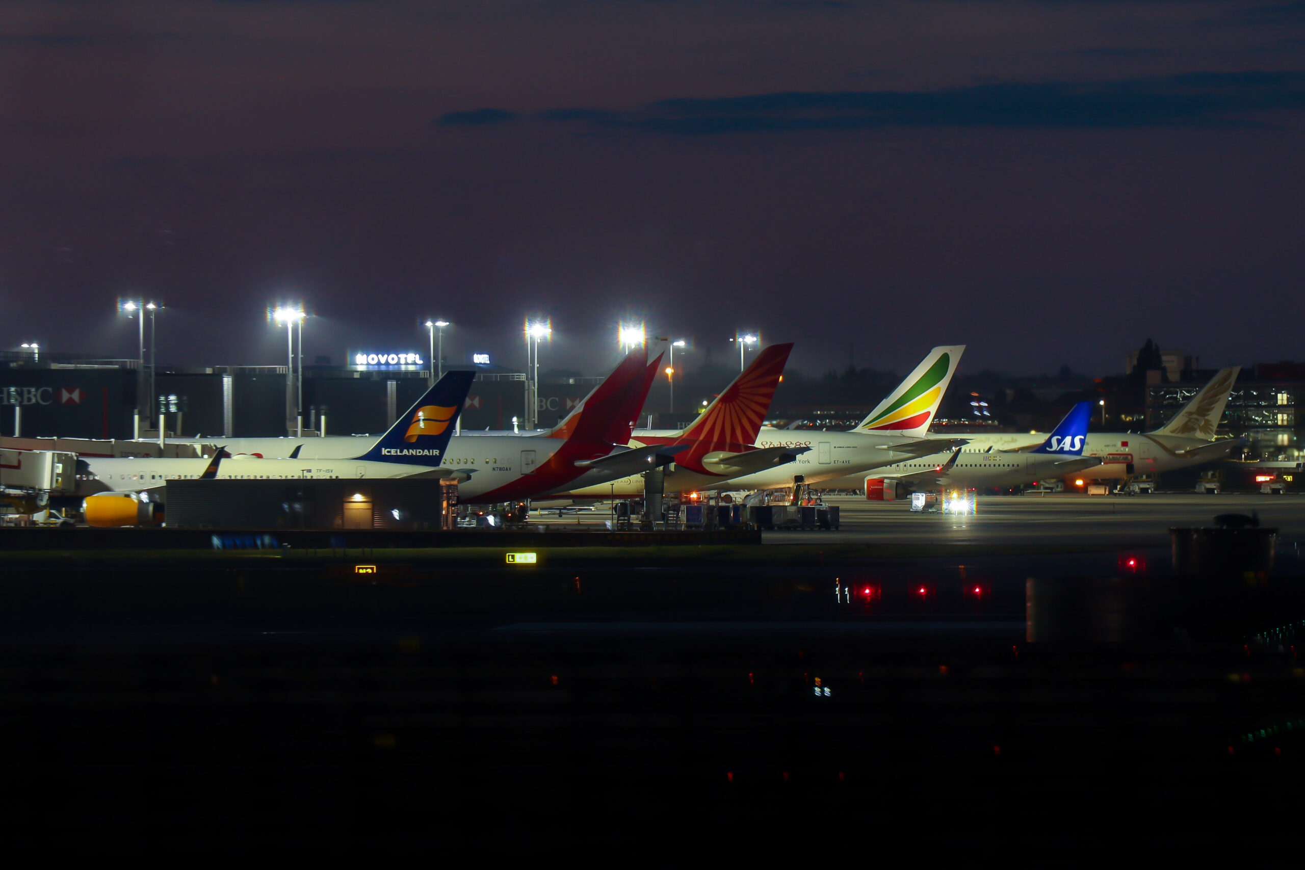 A line of parked aircraft at night.