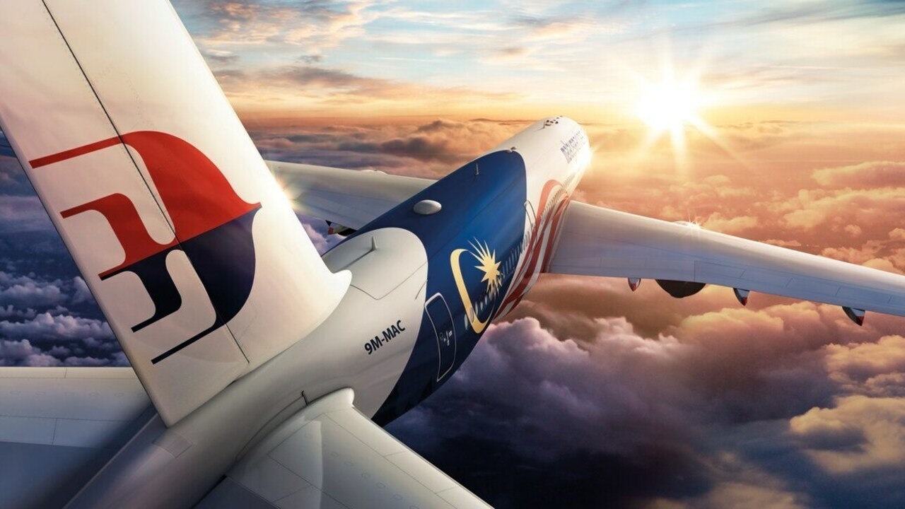 A Malaysia Airlines jet in flight at sunrise.